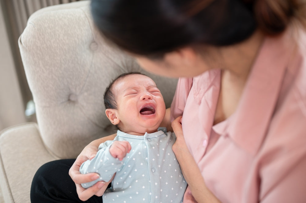 Crying baby in mother’s arms during feeding