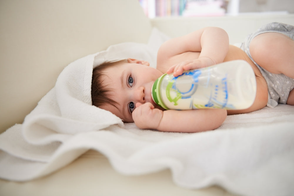 Baby lying on a blanket drinking from a bottle